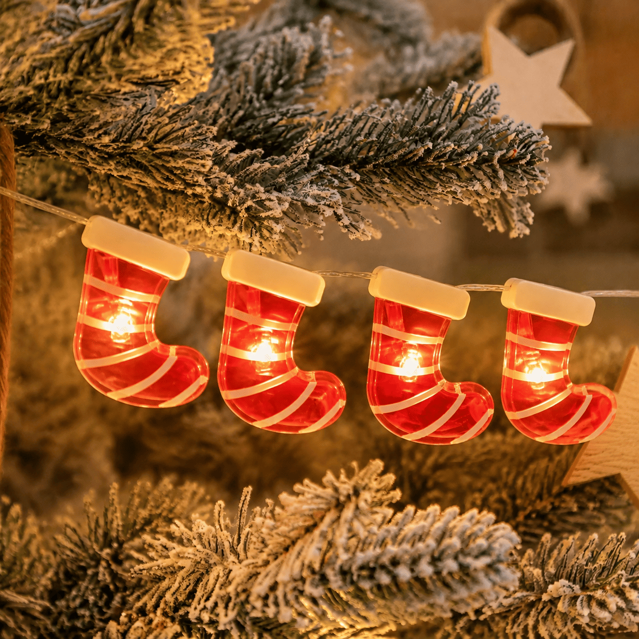 Guirlande lumineuse de Noël à chaussettes rayées rouges et blanches, allumée sur des branches de sapin.