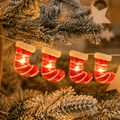 Guirlande lumineuse de Noël à chaussettes rayées rouges et blanches, allumée sur des branches de sapin.